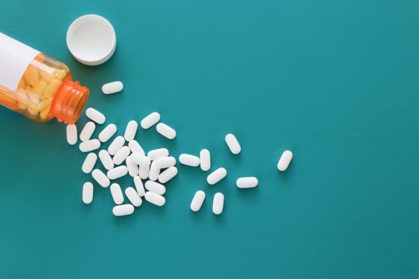 Bottle of spilled pills on a blue background