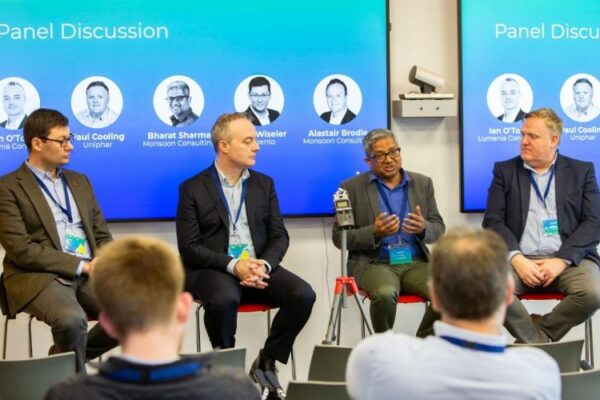 Four men sit on chairs on stage at a panel discussion