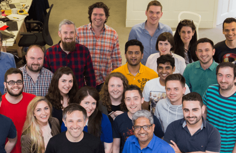 A group of around 20 people smiling and looking up at the camera
