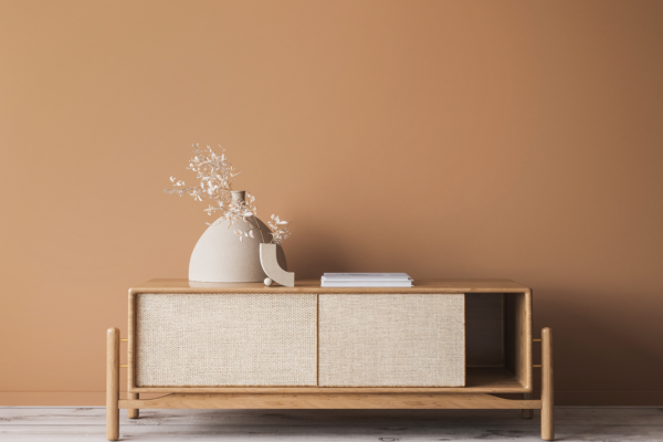 Wooden shelving with fabric beige cover and a vase and books on top in a beige and light brown colour scheme