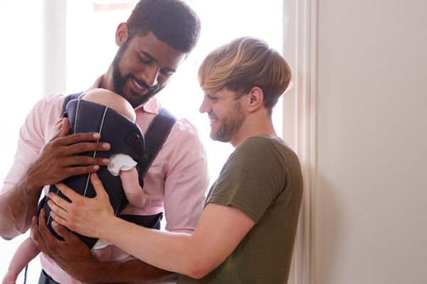 two men hold a small baby