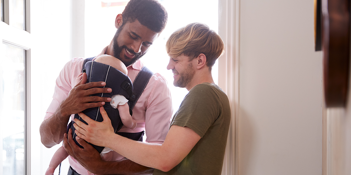 two men hold a small baby