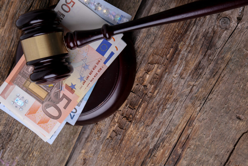 A stack of Euros with a wooden gavel on a table
