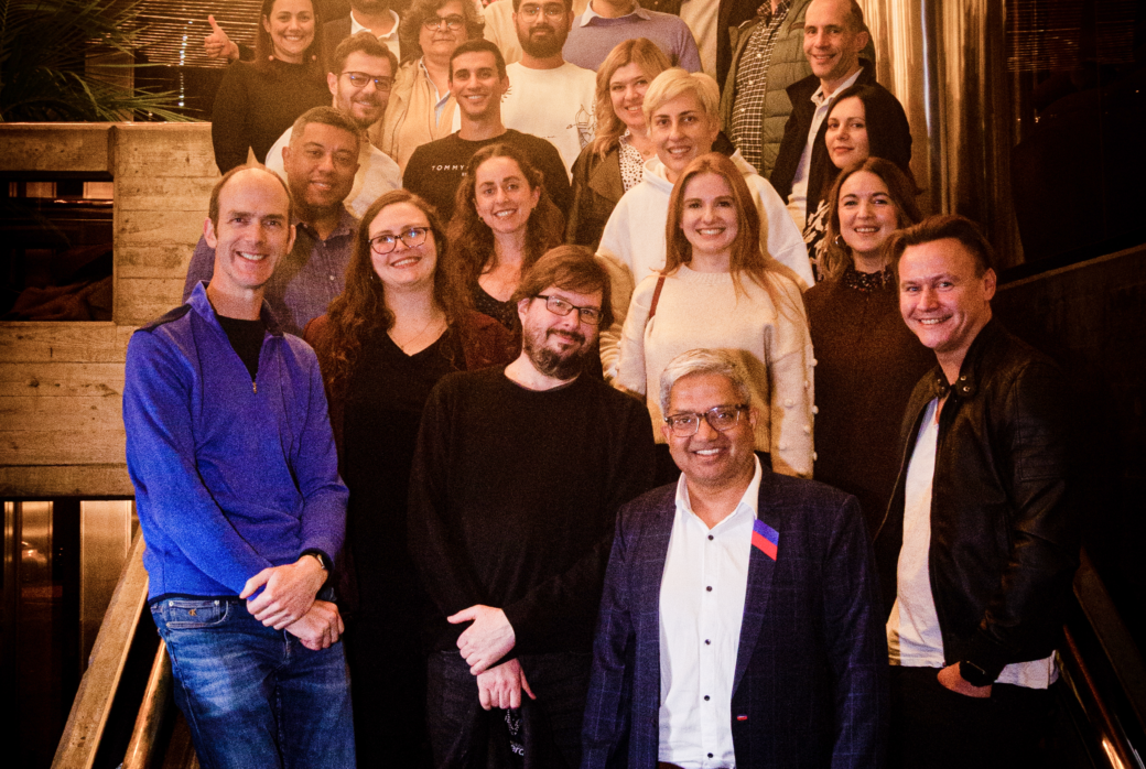 Group photo on a staircase with a bright chandelier in the top left