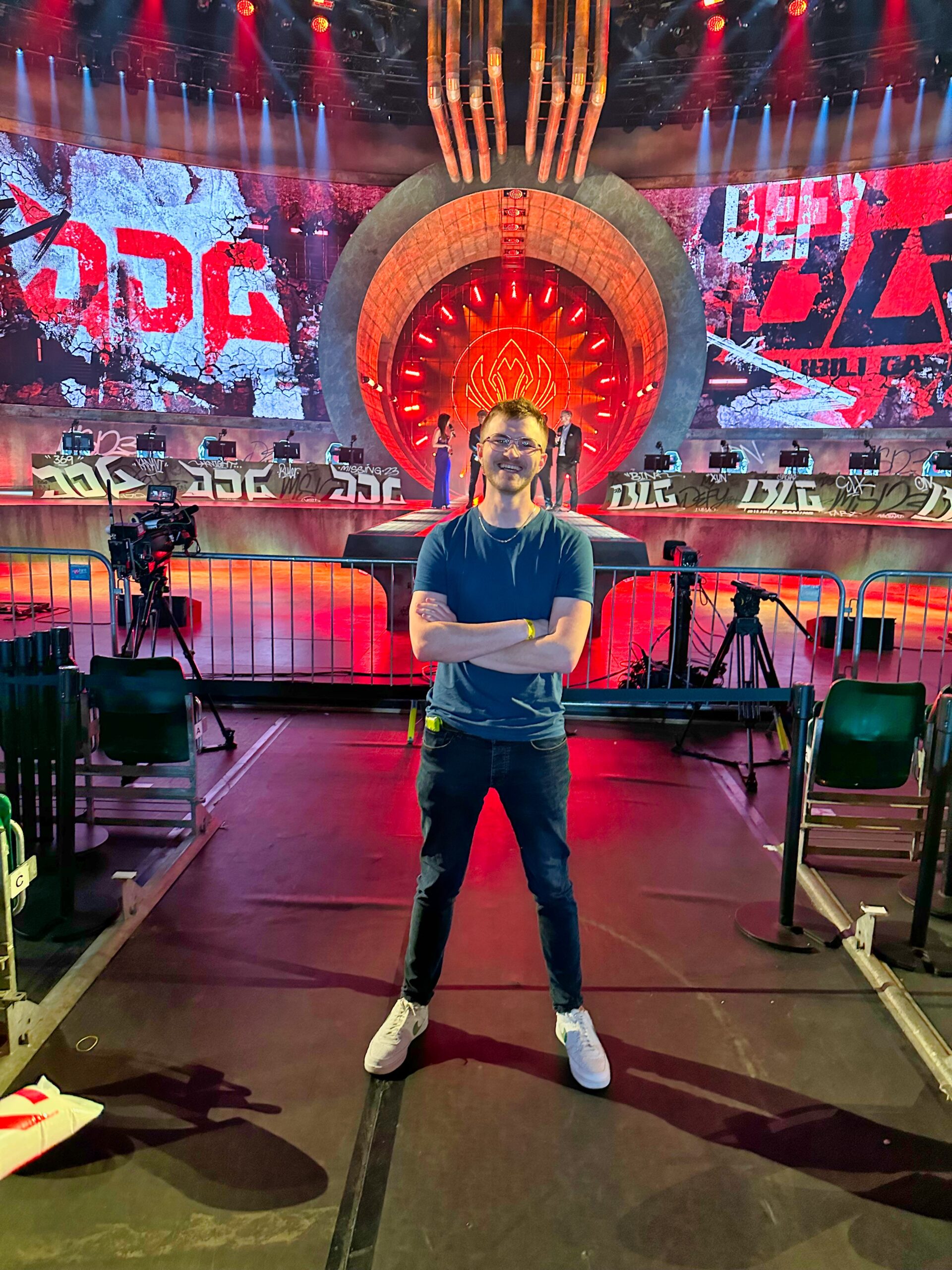 Man standing with arms crossed in an esports arena
