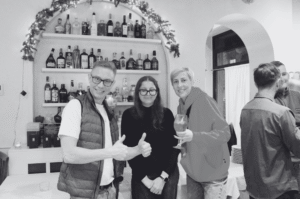 Man and two women smiling in front of shelve with bottles behind