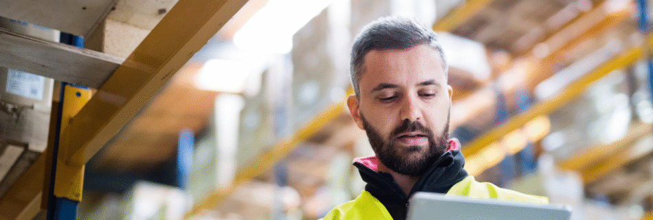 Man in a warehouse reviewing a tablet for eCommerce using OroCommerce
