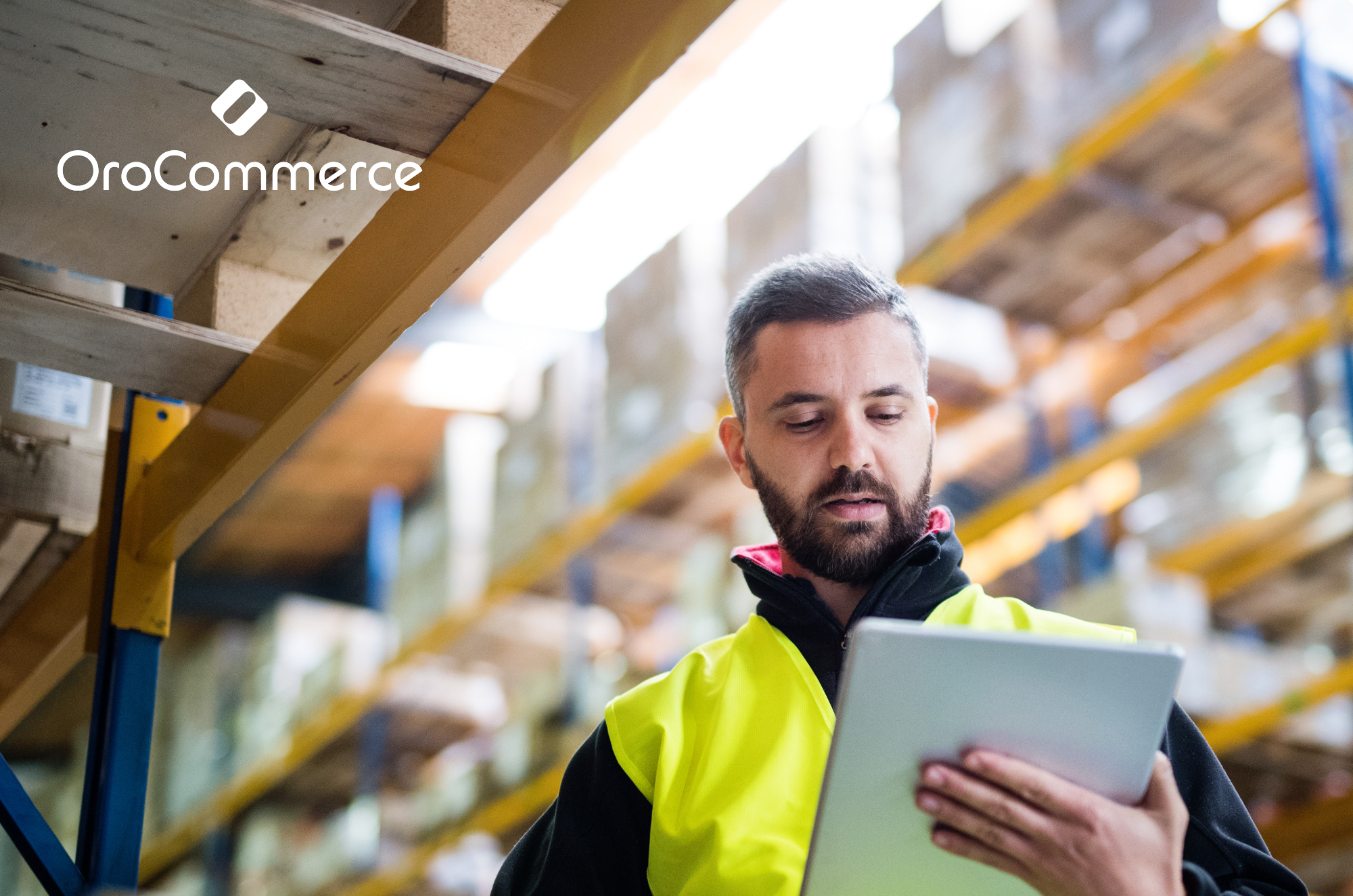 Man in a warehouse reviewing a tablet for eCommerce using OroCommerce