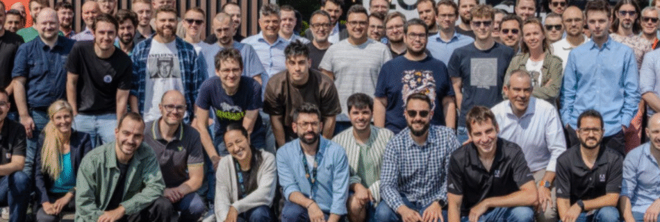 A group of around 50 people posing for a picture in front of an office