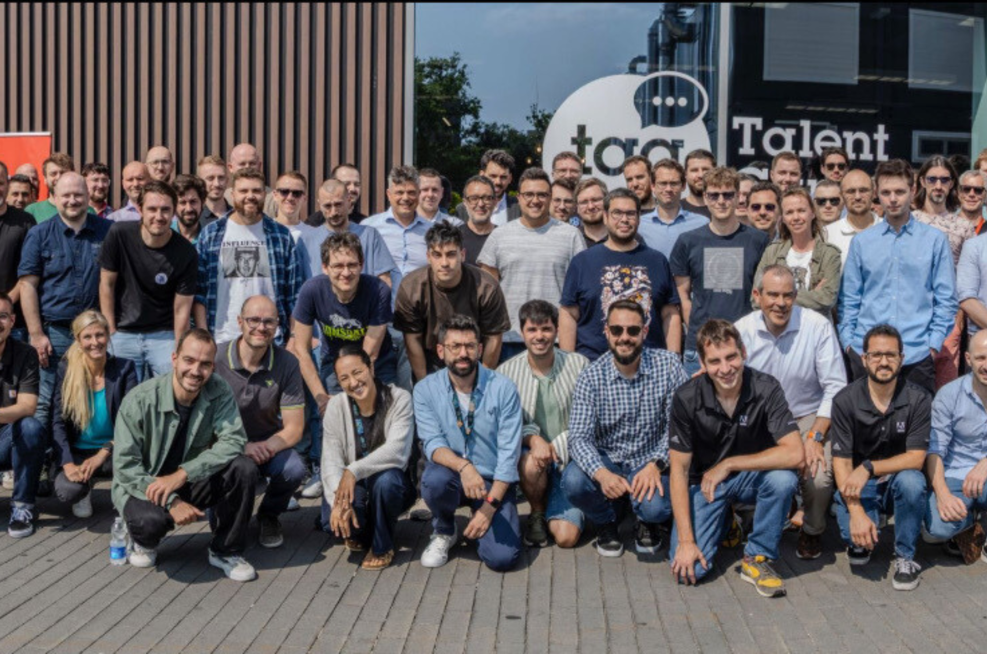 A group of around 50 people posing for a picture in front of an office